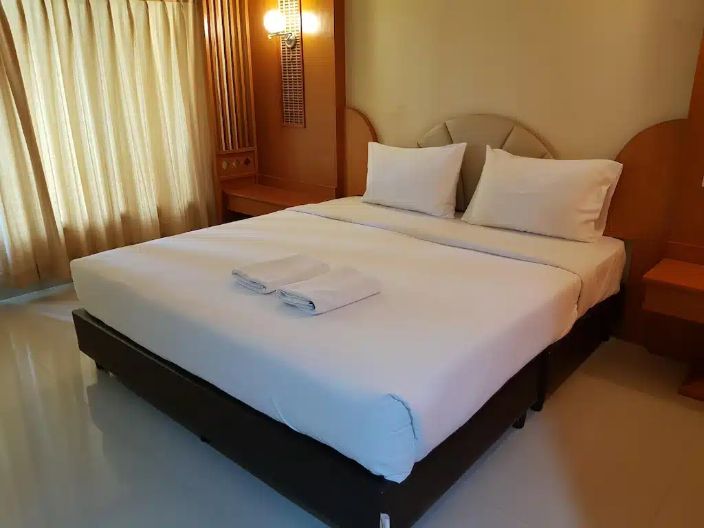 เตียงนอนในห้องที่มีผ้าปูสีขาวและผ้าขนหนูที่สถานที่ท่องเที่ยวแห่งหนึ่งในจังหวัดพิษณุโลก ที่เที่ยวพิษณุโลก