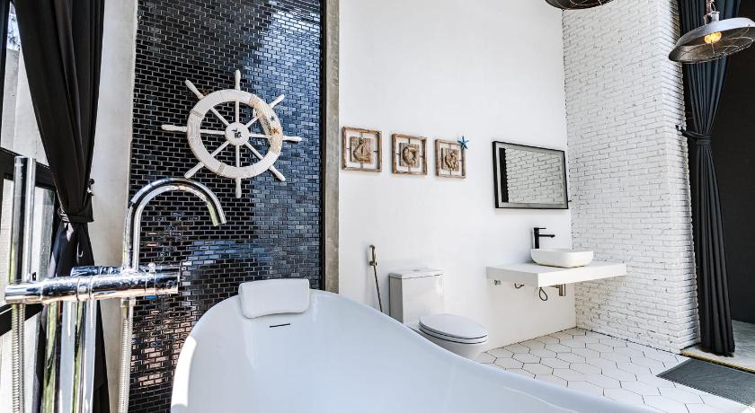 ห้องน้ำของโรงแรมขาวดำพร้อมอ่างอาบน้ำและอ่างล้างหน้า ที่พักทับสะแก