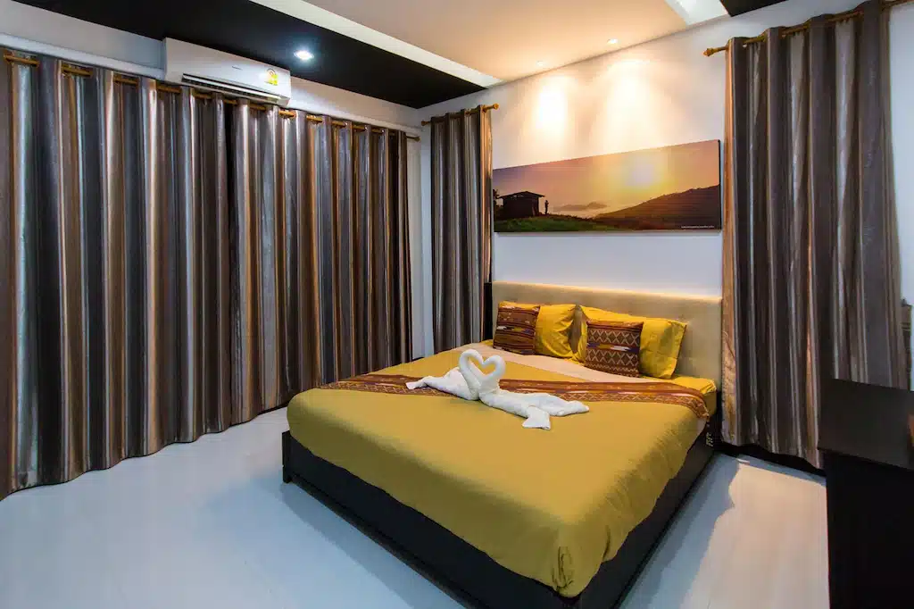 ห้องนอนที่มีเตียงสีเหลืองและผ้าม่านสีขาวตั้งอยู่ใกล้กับวัดเขาสามมุข ดอยเสมอดาว