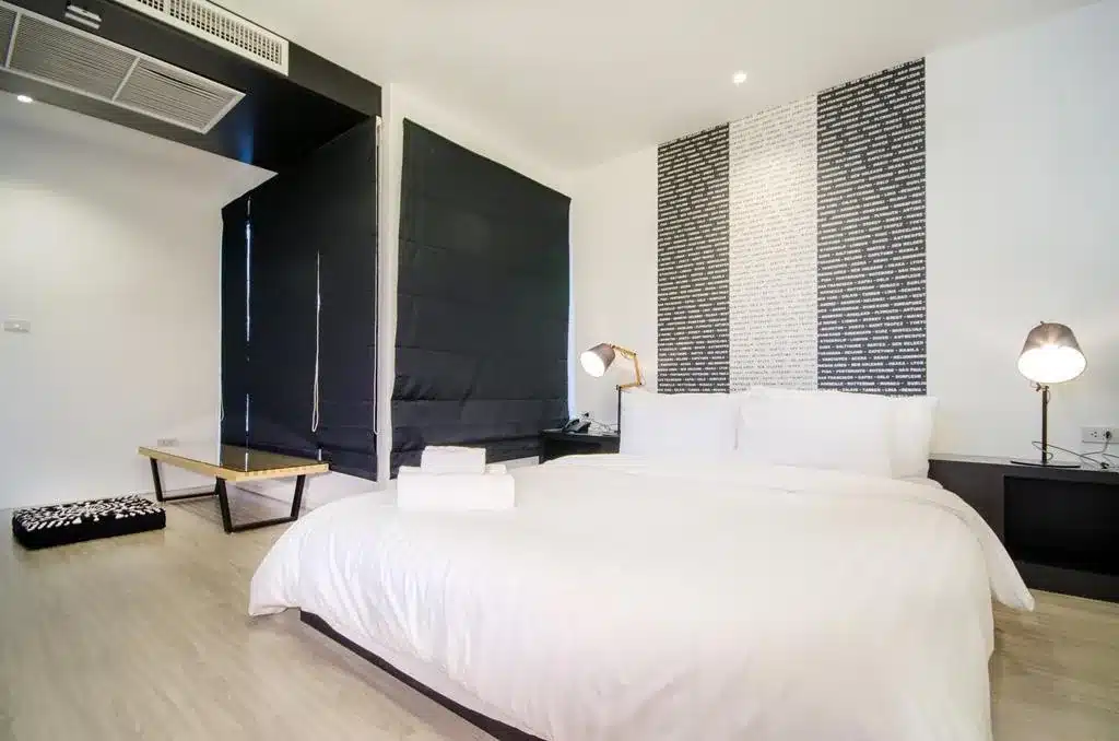 ห้องนอน ที่พักหาดสวนสน หาดสวนสนที่มีเตียงสีขาวและผนังสีดำ