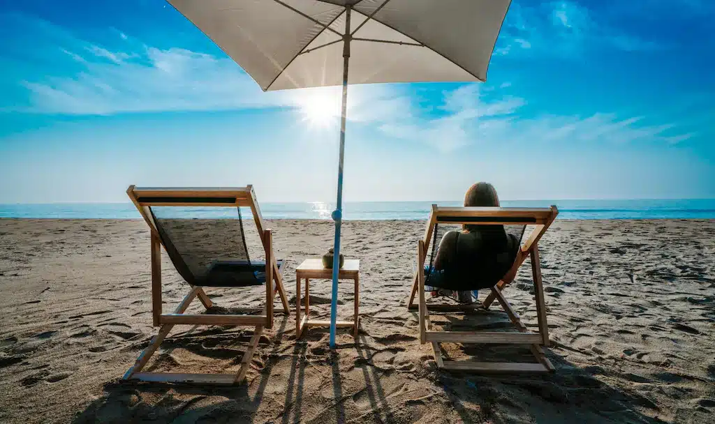 คน 2 คนกำลังนั่งอยู่บนเก้าอี้บนชายหาดในรีสอร์ทภายใต้ร่ม ที่พักทับสะแก