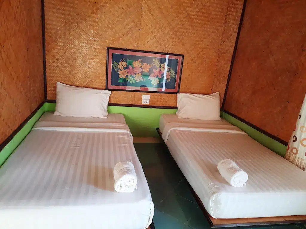 มีแม่สายพร้อมผนังสีเขียวและเตียงสองเตียงในห้อง ที่พักแม่สาย
