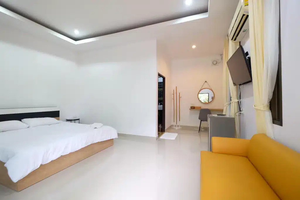 ห้องนอนสีขาวพร้อมโซฟา ที่เที่ยวพิจิตร สีเหลืองและทีวี