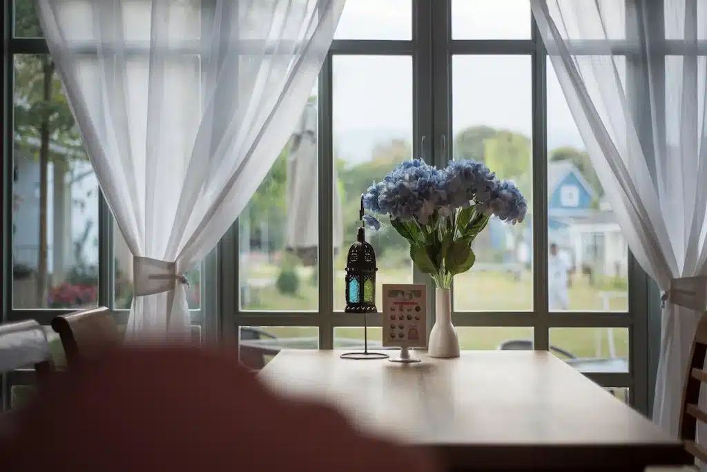 โต๊ะริมหน้าต่างที่โรงแรมแห่งหนึ่งในแม่สายพร้อมแจกันดอกไม้ ที่พักแม่สาย