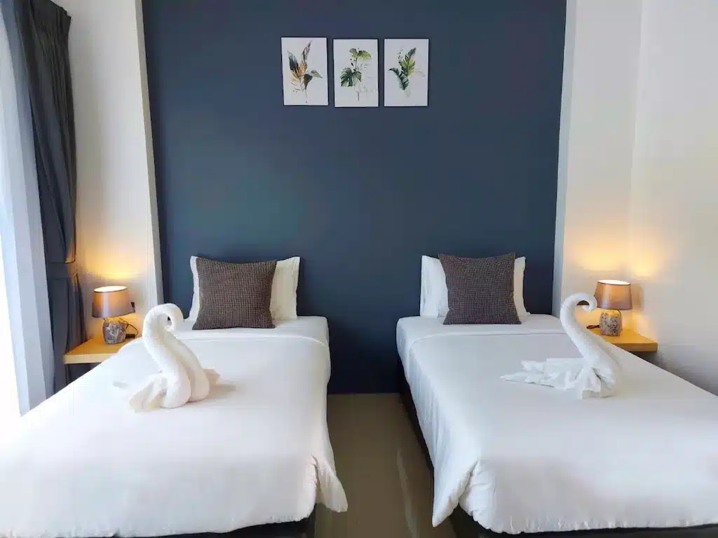 เตียงสองเตียงในห้องที่มีผนังสีฟ้าและหงส์ขาวที่มีลักษณะสิชล รีสอร์ทสิชล