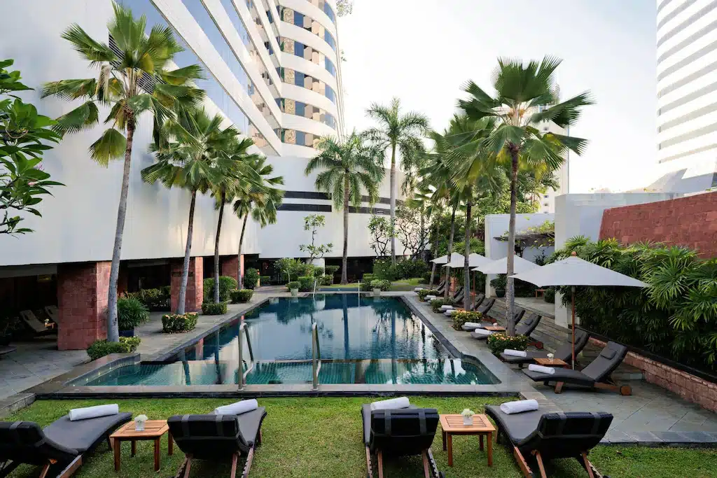 โรงแรมหรูกรุงเทพพร้อมสระว่ายน้ำพร้อมเก้าอี้นั่งเล่นและต้นปาล์ม โรงแรม 5 ดาว ในกรุงเทพ