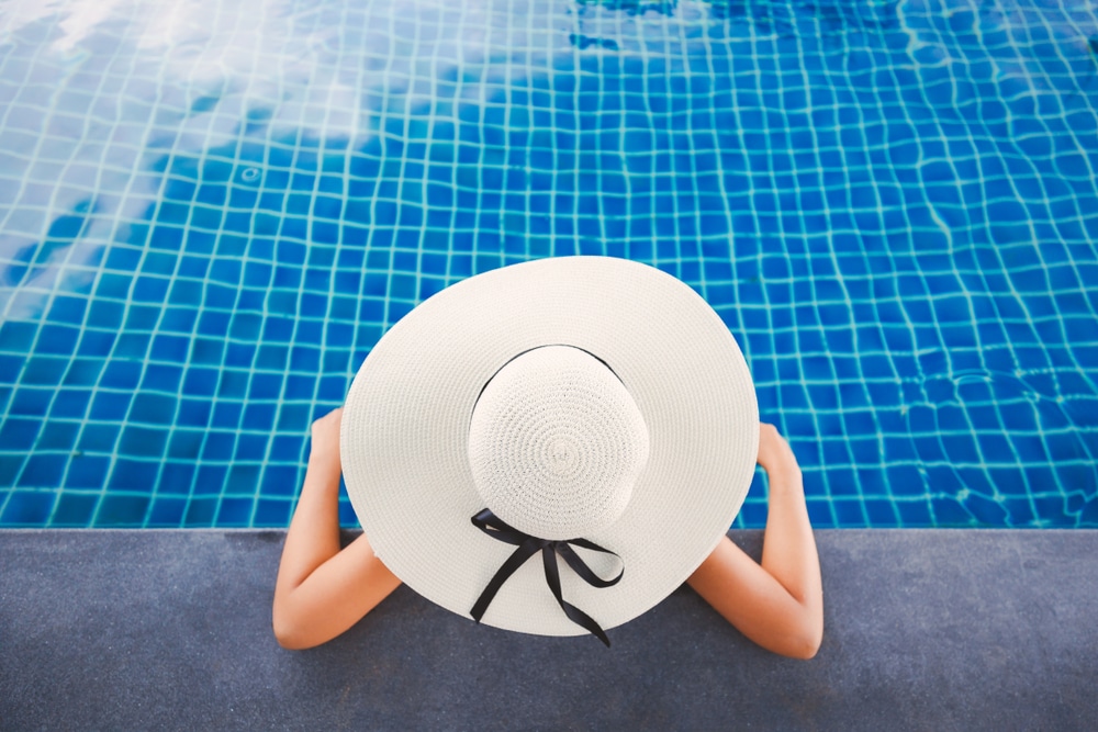 ผู้หญิงสวมหมวกสีขาวกำลังพักผ่อนอยู่ที่ริมสระว่ายน้ำที่หาดแหลมสิงห์