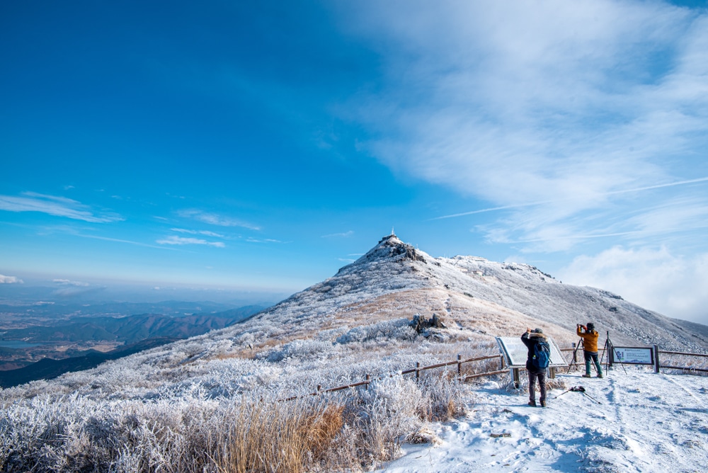 ที่เที่ยวเกาหลี : คนสองคนยืนอยู่บนยอดเขาที่ปกคลุมด้วยหิมะในเกาหลี