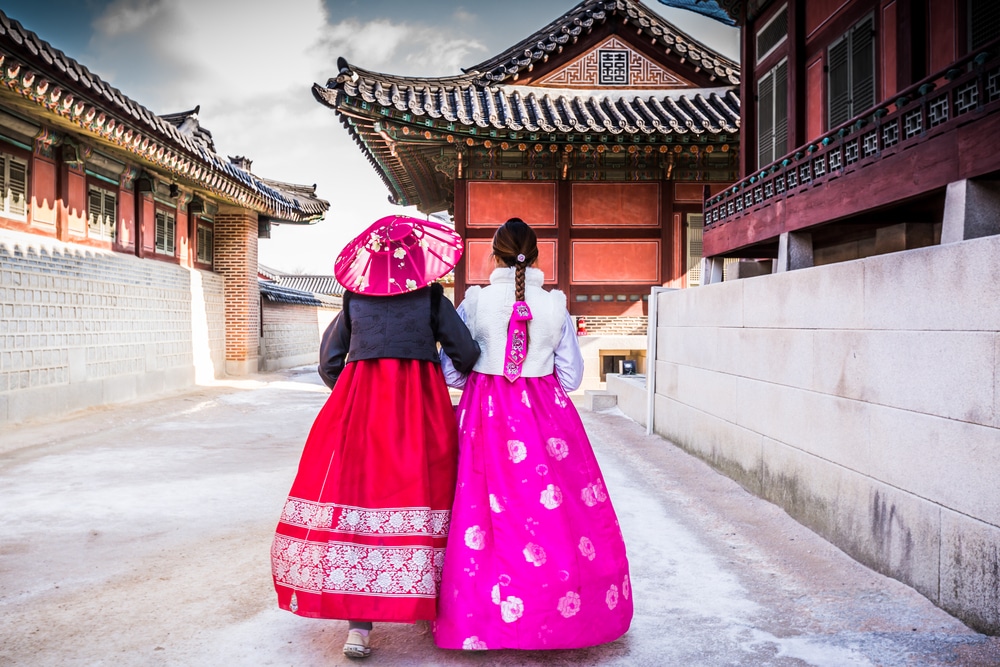 ผู้หญิงสองคนในชุดเกาหลีแบบดั้งเดิมเดินเล่นไปตามถนน ที่เที่ยวเกาหลี