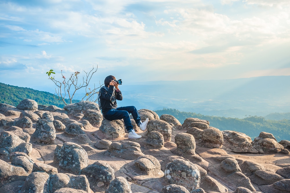 หญิงสาวกำลังถ่ายรูปบนโขดหินที่เที่ยว พิษณุโลกที่เที่ยว ยอดนิยมของไทย