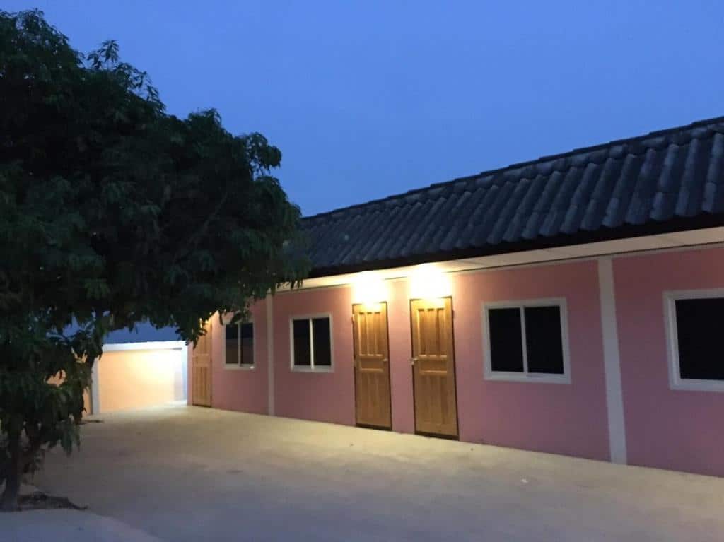 บ้านสีชมพูที่มีหน้าต่างและต้นไม้ในเวลากลางคืน อ่างทองที่พัก