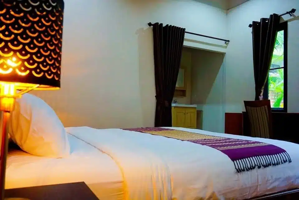 โรงแรมจอมทอง ห้องพักมีเตียงพร้อมโคมไฟติดข้า