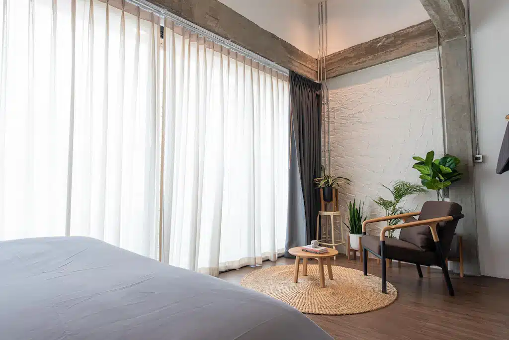ห้องพักในโรงแรมที่มีเตียงและเก้าอี้ริมหน้าต่าง ใกล้อิมแพค เมืองทองธานี ที่พักใกล้อิมแพคเมืองทองธานี