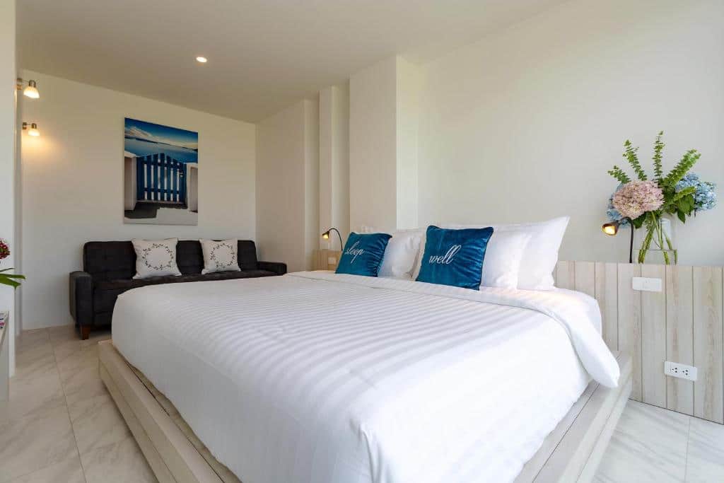 เตียงสีขาวพร้อมหมอนสีฟ้าในห้องนอนริมชายหาดในชลบุรี ที่พักบางเสร่