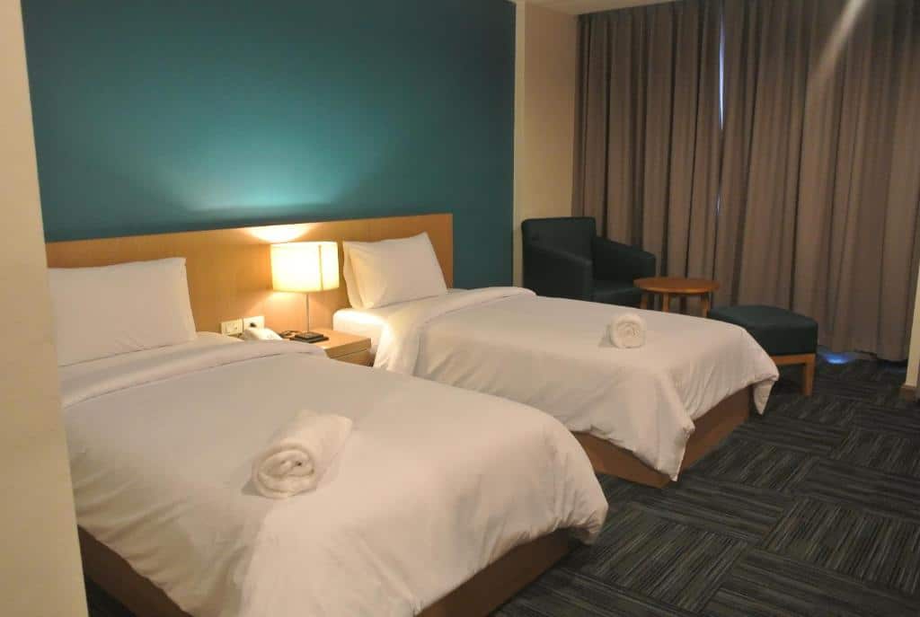 เตียงสองเตียงในห้องพักโรงแรมในสุราษฎร์ธานีที่มีผนังสีฟ้า โรงแรมสุราษฎร์ธานี