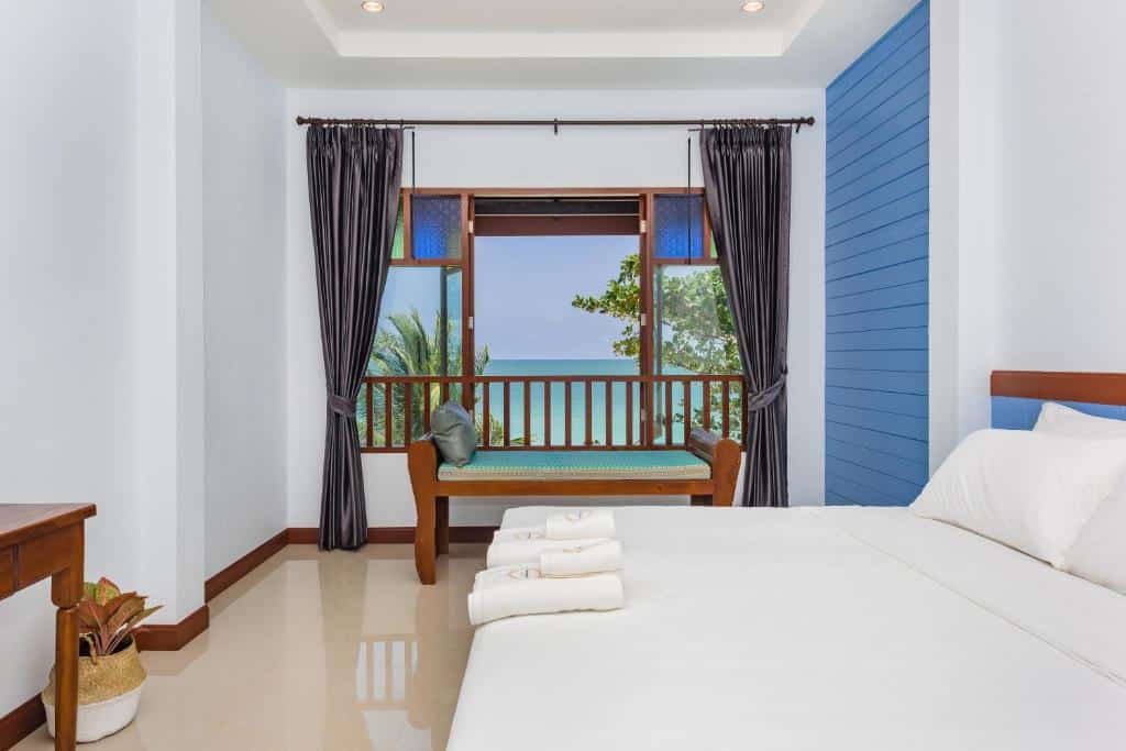 ห้องนอนที่มีผนังสีฟ้าและระเบียงที่มองเห็นวิวทะเล ที่พักติดทะเลขนอม
