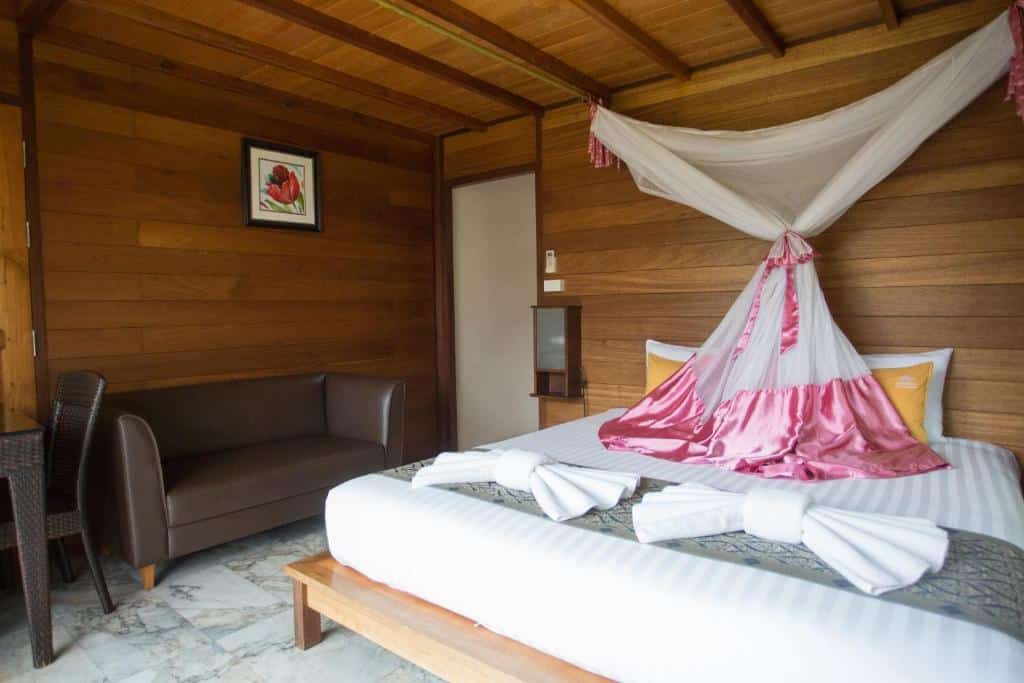 มีสุราษฎร์ธานีไม้มีเตียงที่มีผ้าค โรงแรมในสุราษฎร์ธานี