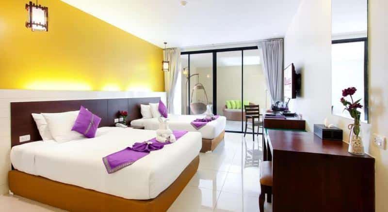 เตียงสองเตียงในห้องพักของโรงแรมที่มีผนังสีม่วงและสีเหลือง โรงแรมเขาตะเกียบ