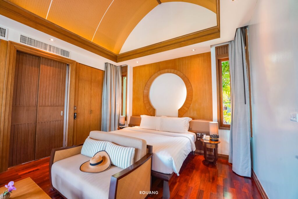 ห้องนอนพร้อมเตียงไม้และเพดานไม้ในสถานที่ท่องเที่ยวชลบุรี ที่พักเขาหลัก