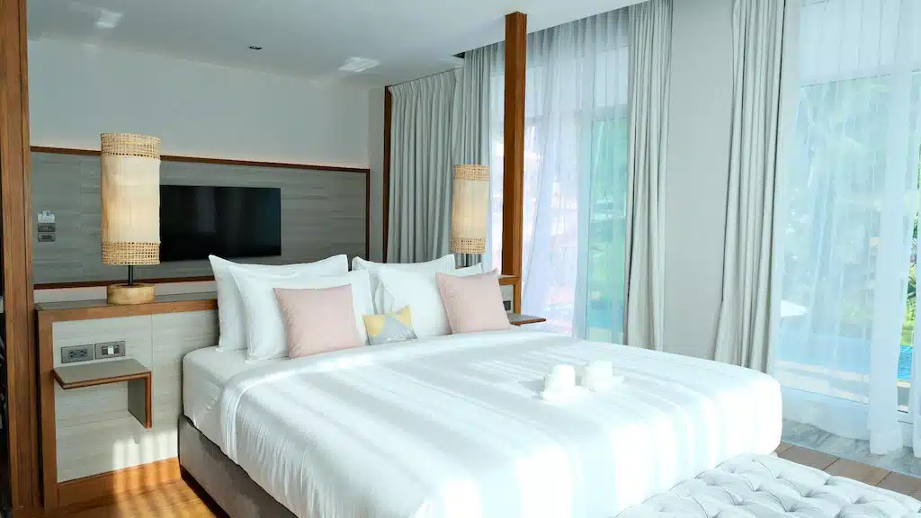 ห้องนอนที่มีเตียงสีขาวและหมอนสีขาว ที่พักขนอมติดทะเล