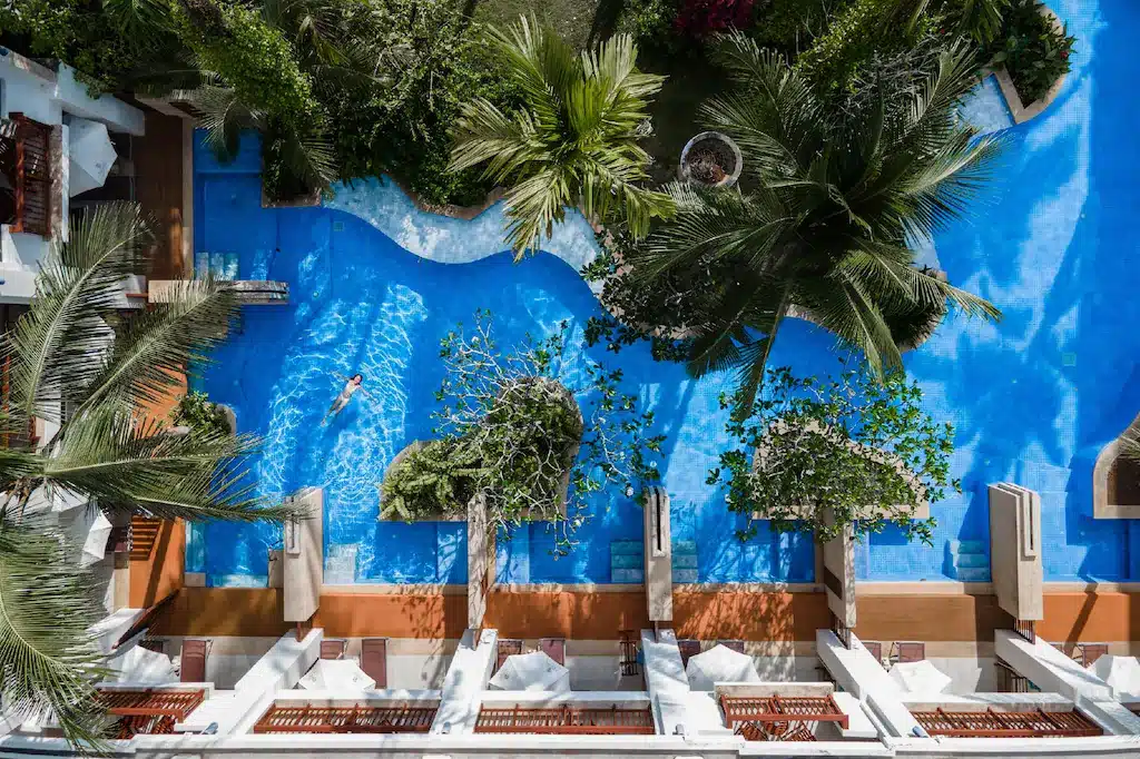 มุมมองทางอากาศของสระว่ายน้ำที่ล้อมรอบด้วยต้นปาล์มในสถานที่ท่องเที่ยวของจังหวัดชลบุรี โรงแรมเขาหลัก