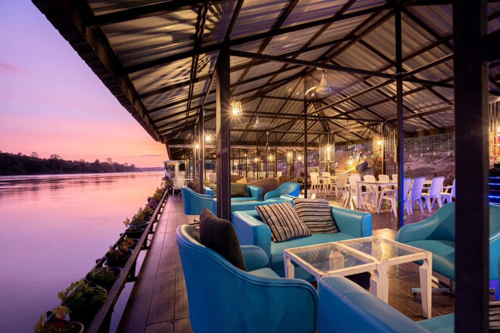 ร้านอาหารบนเรือพร้อมเก้าอี้สีฟ้าและวิวผืนน้ำ ที่เที่ยวอุบลราชธานี