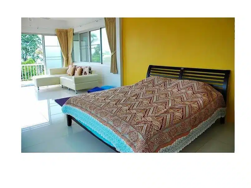 ห้องนอนผนังสีเหลืองและเตียงในรีสอร์ทวังสีเขียว ที่พักวังน้ำเขียว