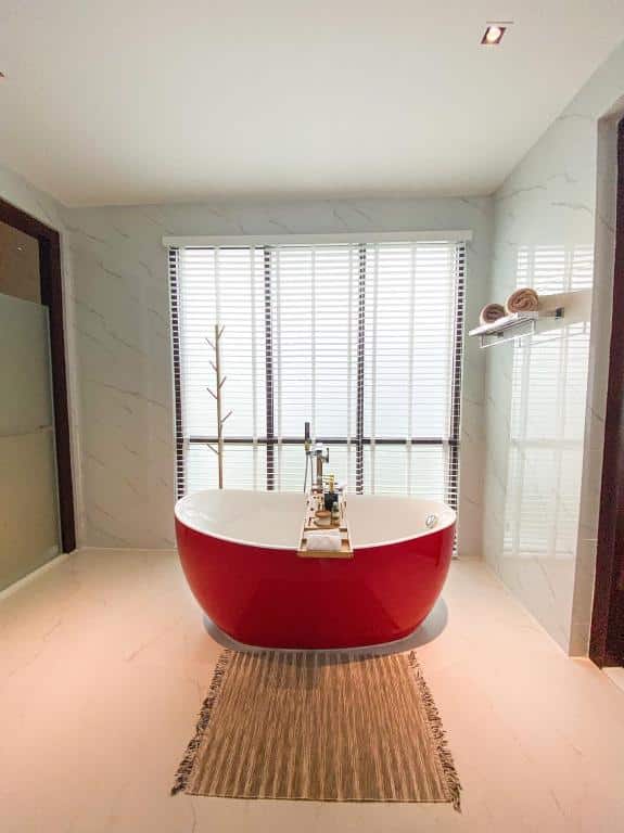 ห้องน้ำพร้อมอ่างอาบน้ำสีแดงและผนังสีขาว ที่พักขนอมติดทะเล