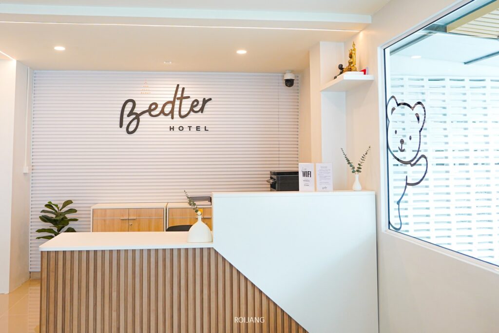 บริเวณแผนกต้อนรับของโรงแรม Bedter มีโต๊ะไม้ ต้นไม้สีสันสดใส และภาพหมีน่ารักบนหน้าต่าง ค้นพบโรงแรมพังงาที่พักที่ถ่ายทอดแก่นแท้ของเสน่ห์ชายฝั่งได้อย่างสมบูรณ์แบบสำหรับการเข้าพักของคุณ