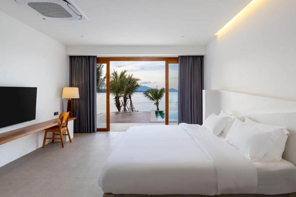 เตียงสีขาวในห้องที่มองเห็นวิวทะเล ที่พักขนอมติดทะเล