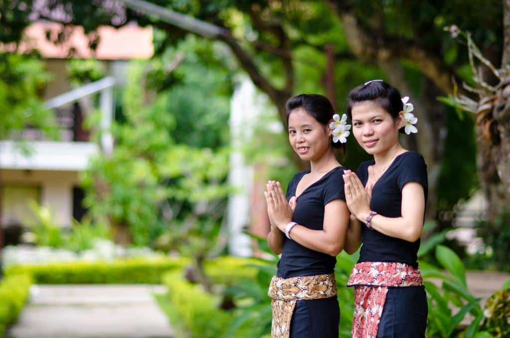 หญิงไทยสองคนยืนอยู่หน้าต้นไม้ที่ โรงแรมจอมทอง ซึ่งเป็นที่พักของพวกเขา