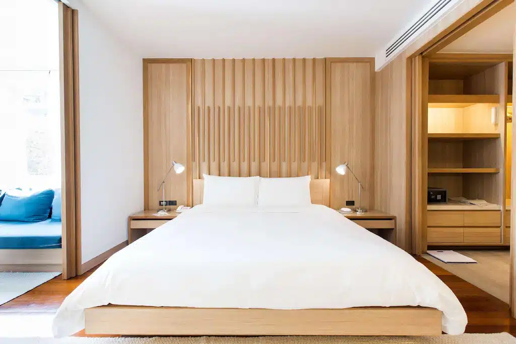 เตียงสีขาวในห้องนอนที่มีผนังไม้ที่โรงแรมป่าตอง