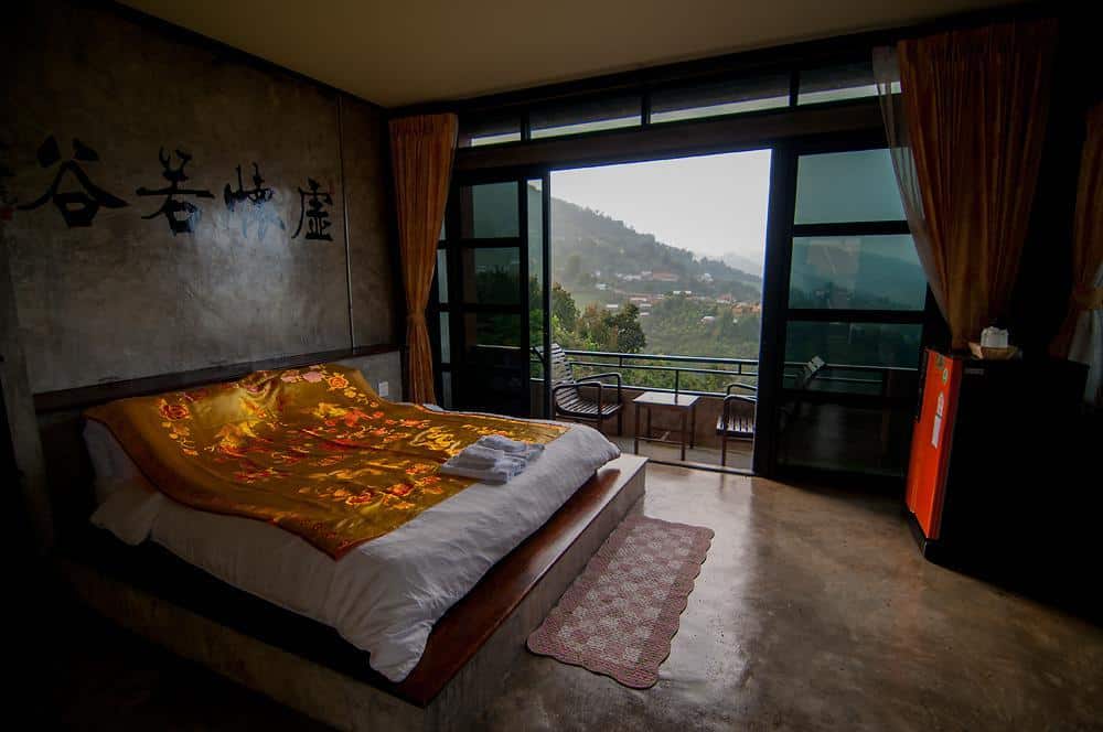 เตียงในห้องที่มองเห็นวิวภูเขาในคุณสมบัติของดอยแม่สลอง ดอยแม่สลองที่พัก