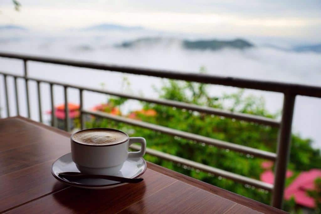กาแฟสักแก้ววางอยู่บนโต๊ะพร้อมวิวภูเขาในน่านที่เที่ยว ดอยแม่สลองที่พัก