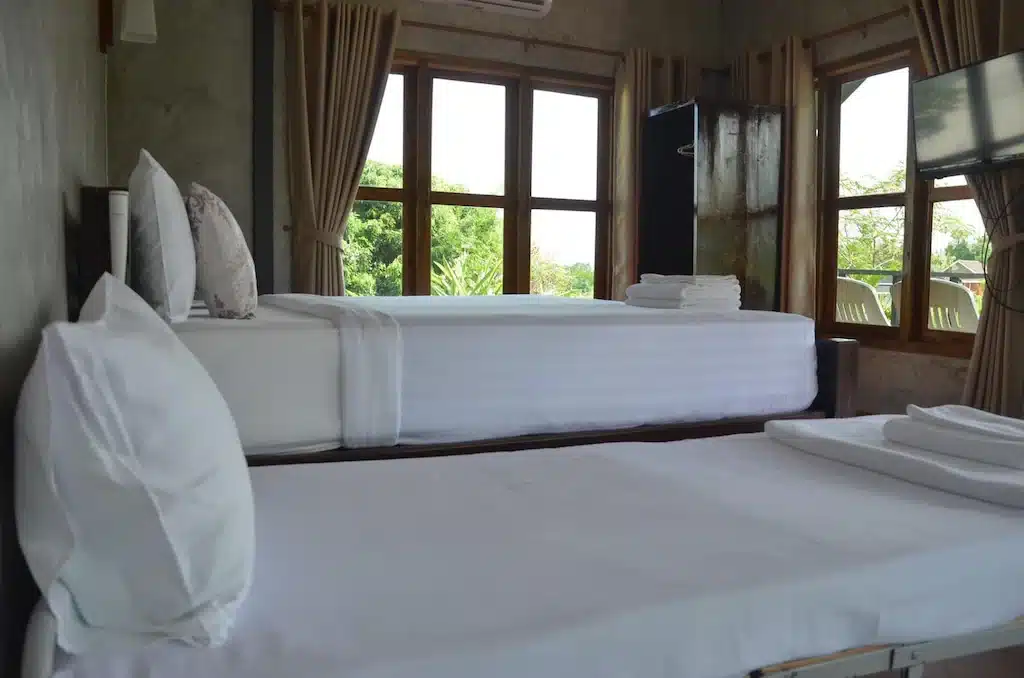 โรงแรมจอมทอง มีเตียงสองเตียงพร้อมผ้าปูที่