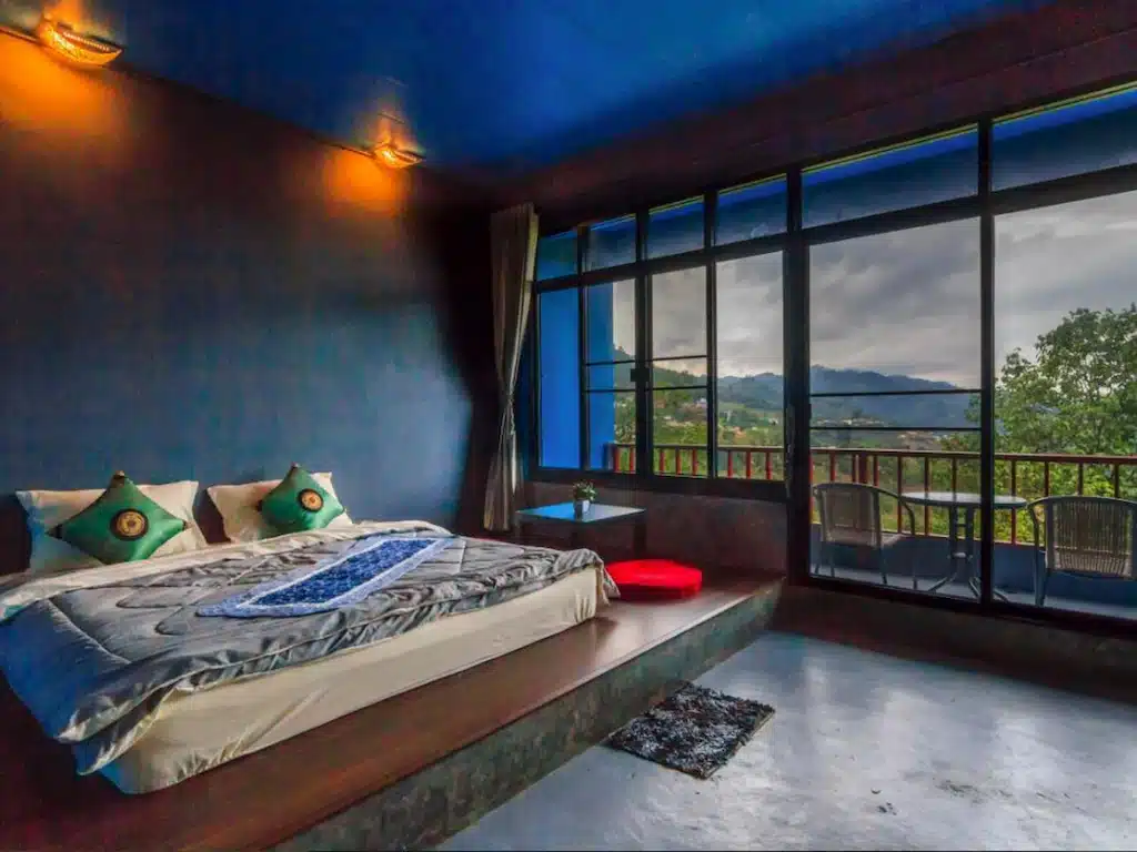ห้องนอนธีมสีฟ้ามีระเบียงพร้อมทิวทัศน์อันตระการตาของภูเขาในเที่ยวน่าน ดอยแม่สลองที่พัก
