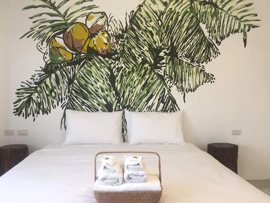 เตียงในห้องที่มีจิตรกรรมฝาผนังรูปต้นปาล์ม ที่พักขนอมติดทะเลราคาถูก
