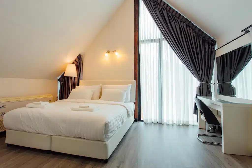 ห้องนอนใต้หลังคาพร้อมเตียงและโต๊ะทำงาน ตั้งอยู่ในชลบุรี โรงแรมลำปาง