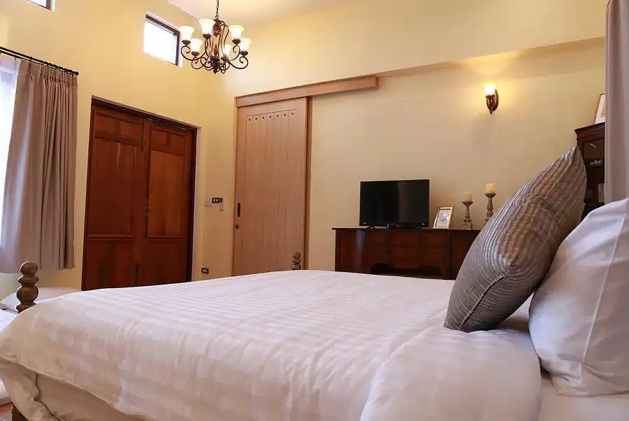 ห้องนอนริมชายหาดพร้อมเตียงขนาดใหญ่และโคมระย้า ที่พัก พูลวิลล่าเขาใหญ่
