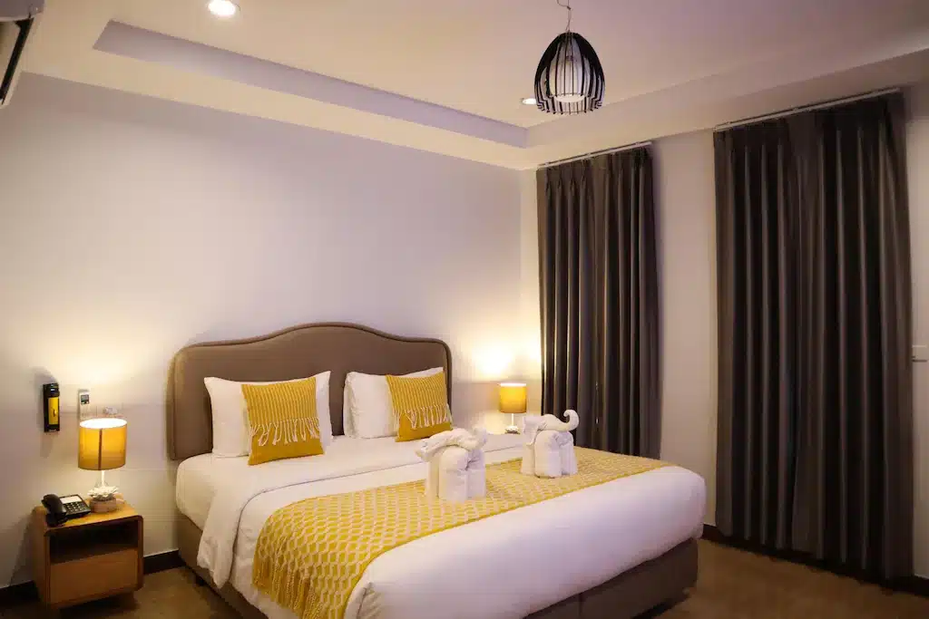 เตียงในห้องที่มีผ้าปูที่นอนสีเหลืองและสีขาว ที่พักขนอมติดทะเล
