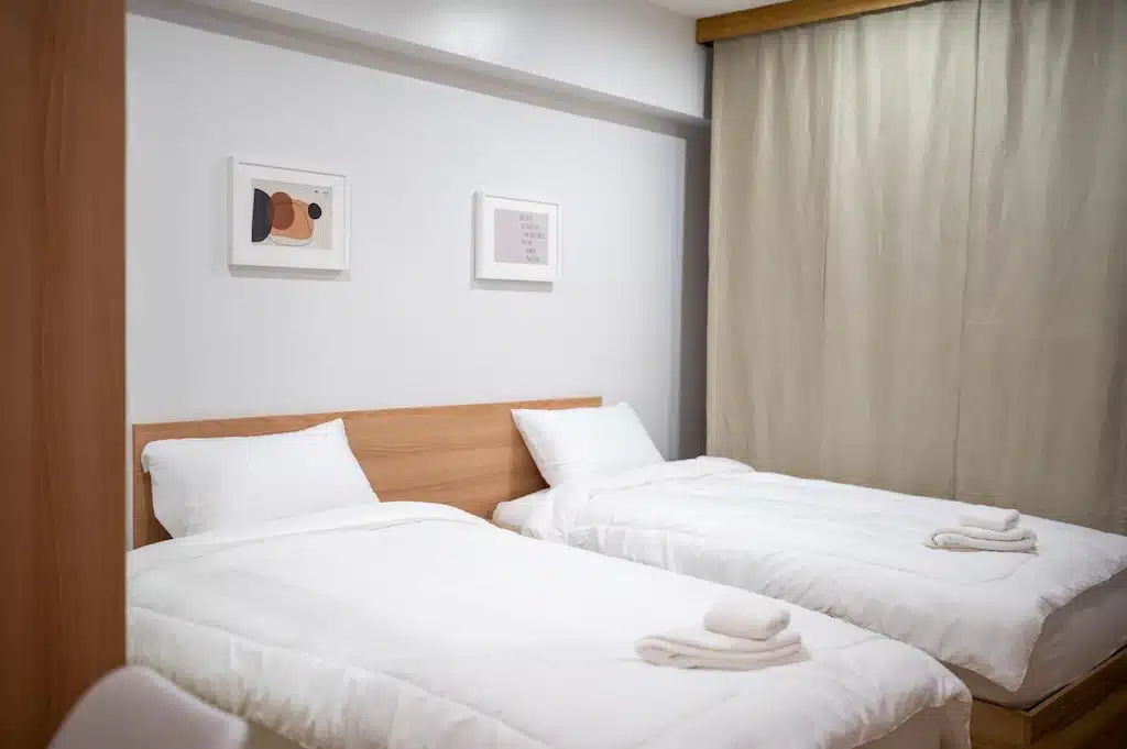สองเตียงในห้องเล็ก ๆ ที่มีผ้าปูที่นอนสีขาวที่พัทลุง ที่พักสุพรรณบุรี