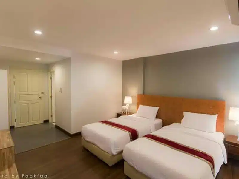 เตียงสองเตียงในห้องพักของโรงแรมที่มีพื้นไม้ ที่เที่ยวดอยช้าง