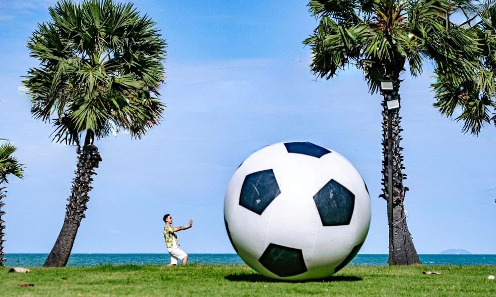 ลูกฟุตบอลขนาดใหญ่บนพื้นหญ้าข้างต้นปาล์มที่โรงแรมโมเวนพิค สยาม นาจอมเทียน พัทยา โรงแรมเมอเวนพิคสยามโฮเทล