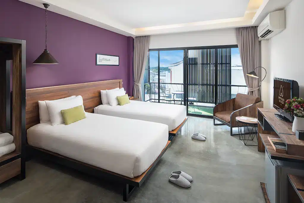 โรงแรมสมุทรสงคราม: สองเตียงในห้องที่มีผนังสีม่วงที่โรงแรมแห่งหนึ่งในจังหวัดสมุทรสงครามที่พ ที่พักสมุทรสงคราม