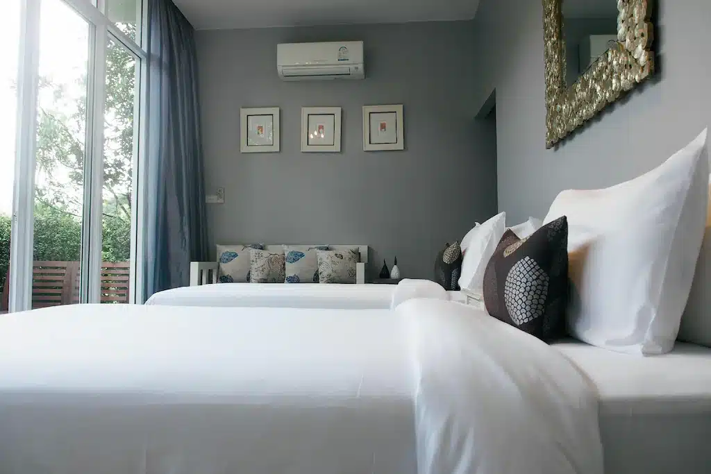 ห้องที่มีเตียงสองเตียงและหน้าต่างในโรงแรมแห่งหนึ่งในเมืองระนอง ที่พักระนอง