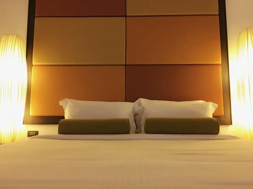 เตียงในห้องพักของโรงแรมพร้อมโคมไฟ 2 ดวงที่มีฟังก์ชั่นหนองคาย ที่พักริมโขงหนองคาย
