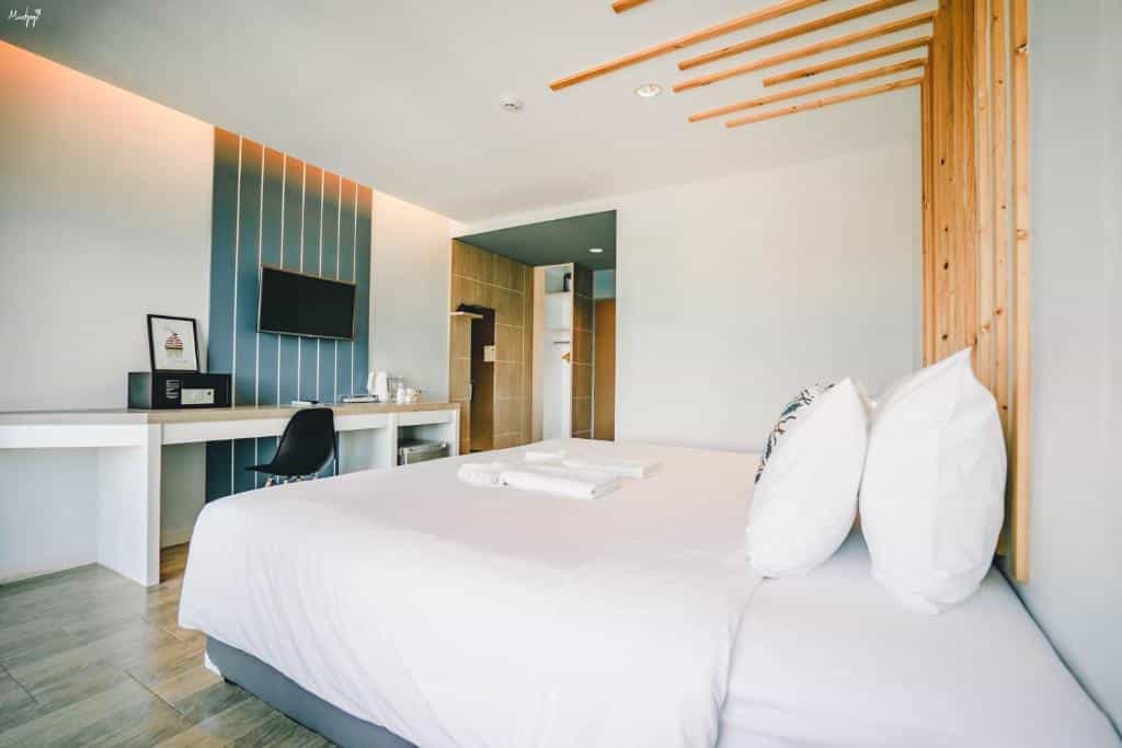 เตียงในห้องที่มีพื้นไม้ที่โรงละครระนองหรือ โรงแรมระนอง  บ้านไร่ไออรุณ