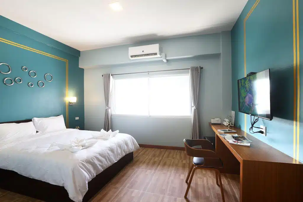 ห้องพักในโรงแรมที่มีผนังสีฟ้าและพื้นไม้ ที่พักพัทลุง