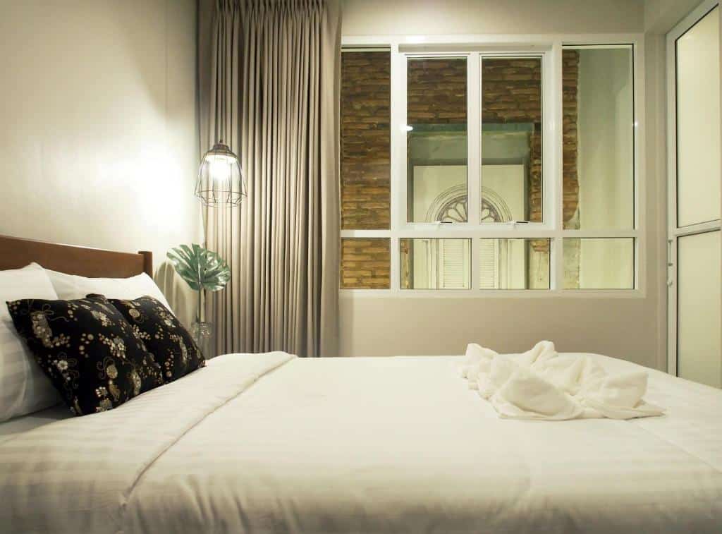 เตียงสีขาวในห้องที่มีหน้าต่ ที่พักระนองติดทะเล างที่โรงแรมระนอง ที่พักระนองในเมือง