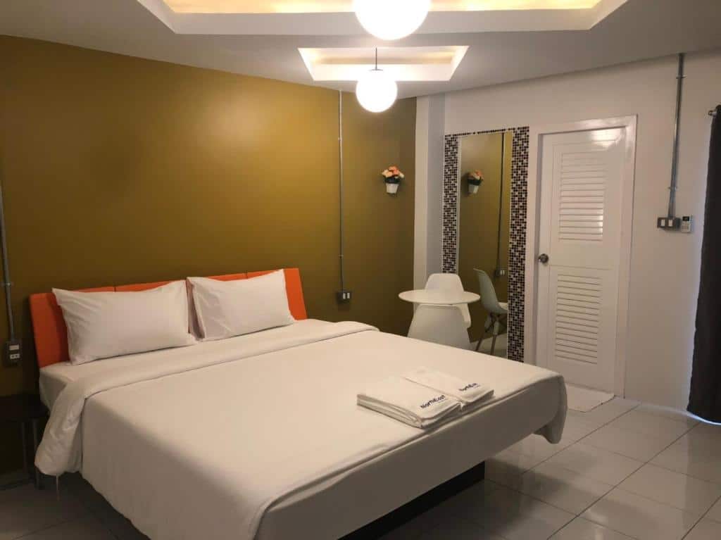เตียงในห้องที่มีผนังสีเหลืองเน้นสีส้มที่โรงแรมรีสอร์ทในจังหวัดศรีสะเกษ  รีสอร์ทศรีสะเกษ